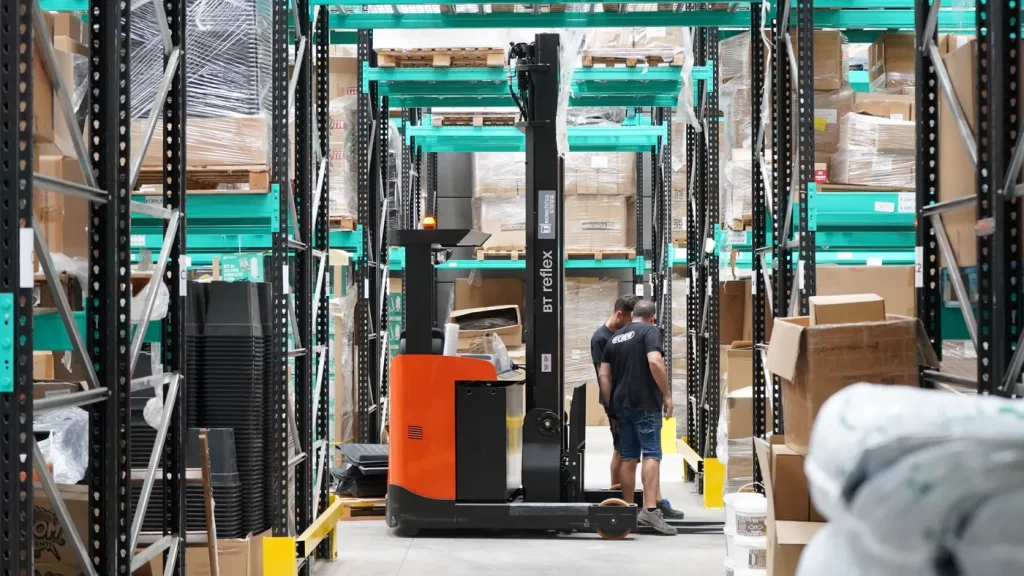 Reach truck working between warehouse racks