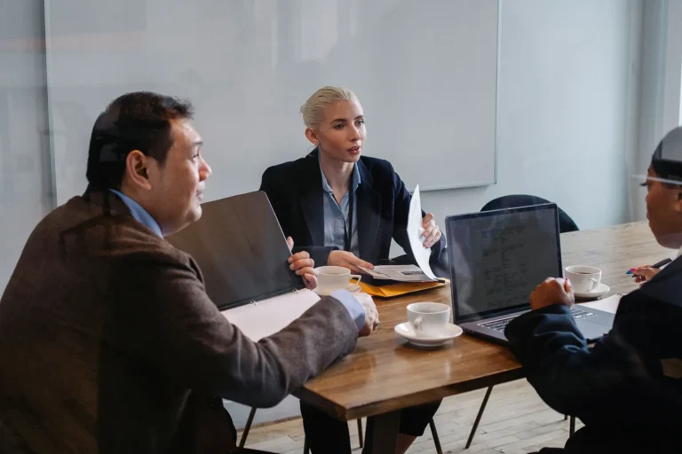 Three people in a meeting with a laptop